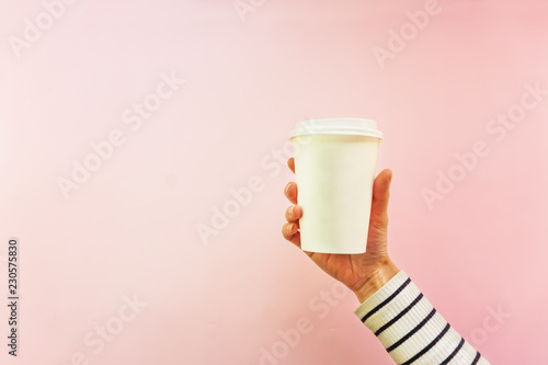 Creative mock up image of woman hand holding craft paper coffee cup with copy space isolated on white background in minimalism style. Template for feminine blog, social media