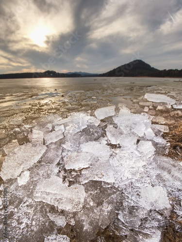 Pieces of clear natural ice on frozen lake,  very close up view. Early mealting of ice photo