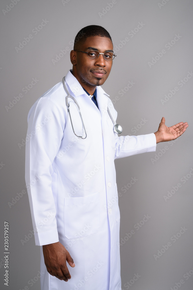 Young handsome African man doctor against gray background Young handsome African man doctor against gray background