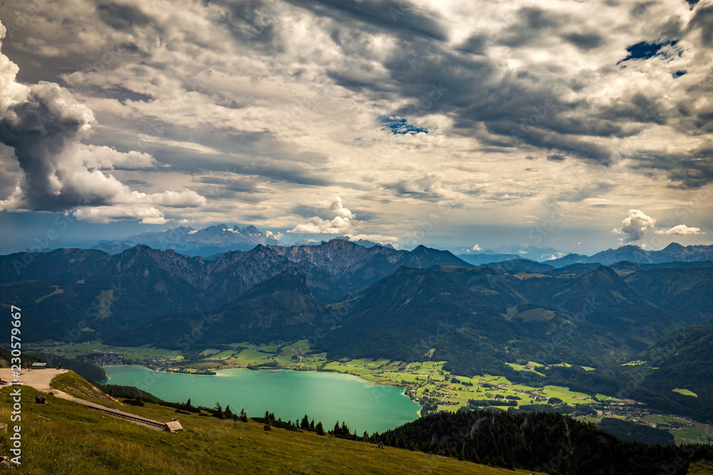 Panoramic view of mountains from Schafberg peak in Salzkammergut, Austria in a beautiful summer day with dramatic clouds and Wolfgang see in the background