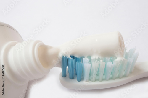 Squeezing toothpaste onto toothbrush on white background
