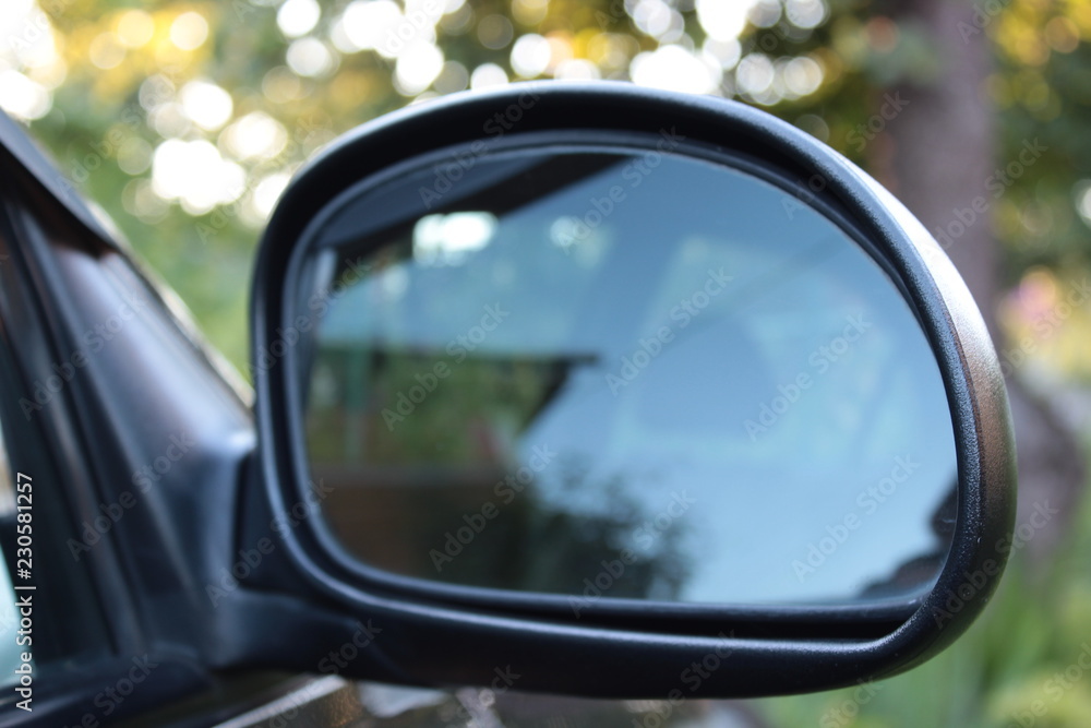 Car mirror on the green background. Blue sky, mirroring. Sunny day