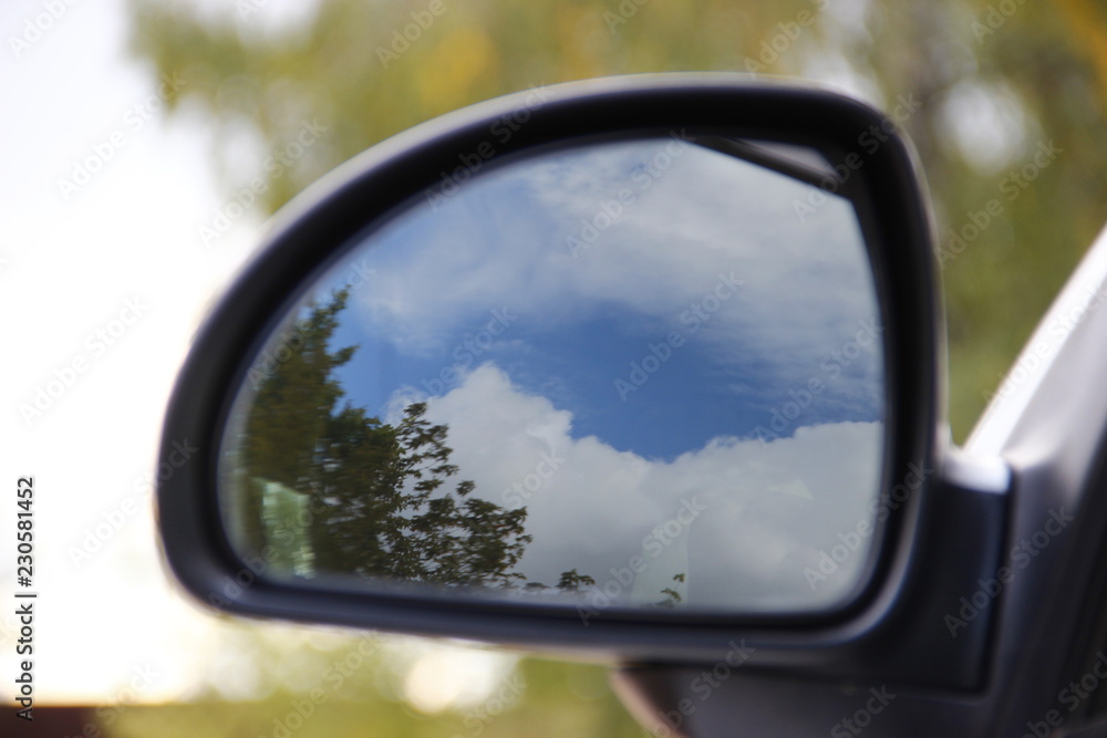 Car mirror on the green background. Blue sky, mirroring. Sunny day