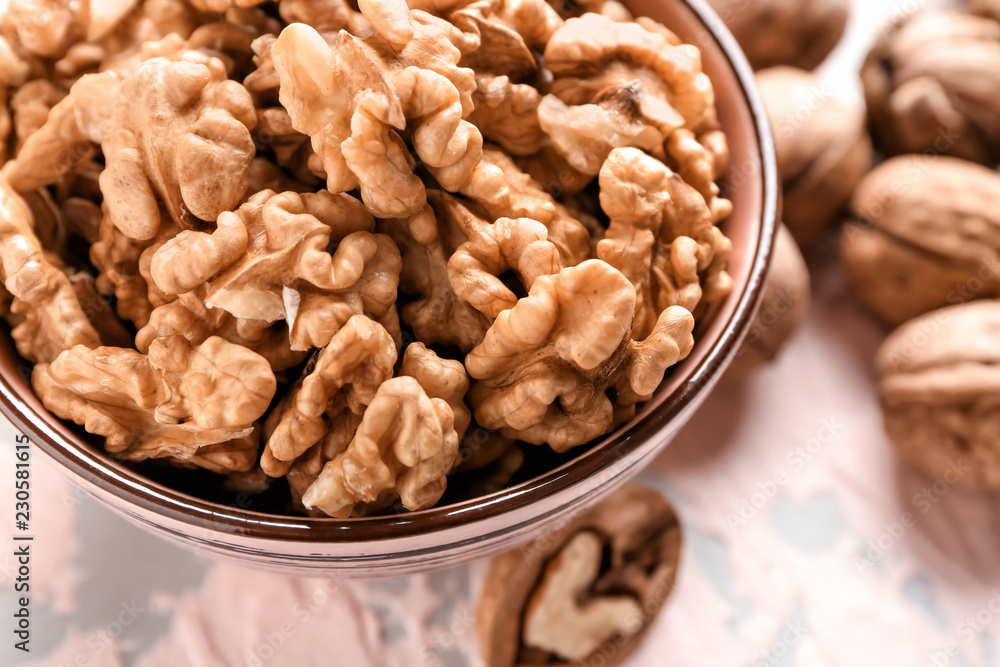 Bowl with tasty walnuts on color table, closeup Bowl with tasty walnuts on color table, closeup