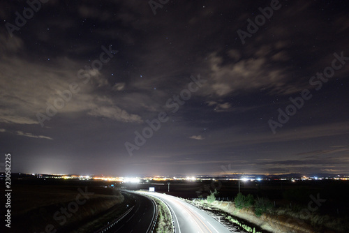 Motorway illuminated by the lights of the cars with the population of Almagro in the background.
