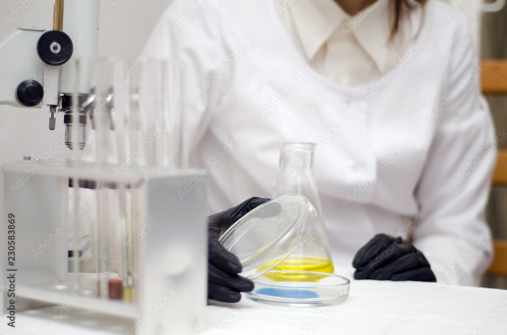 Fototapeta premium laboratory worker in a white coat working with chemicals under a microscope