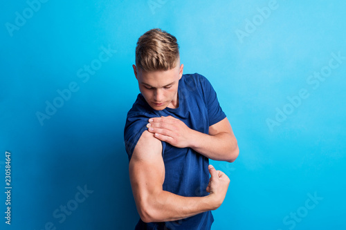 Fotobehang Portrait of a cheerful young man in a studio, flexing muscles.