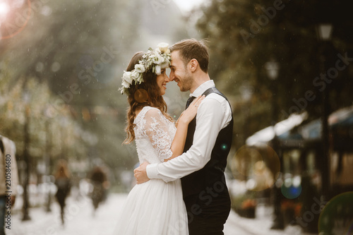 Happy bride and groom after wedding ceremony embracing in rain photo