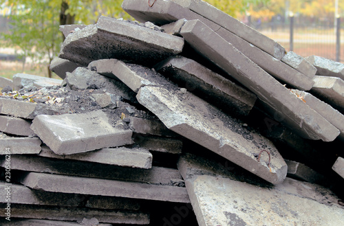  A large pile of broken, gray biton slabs lies on the ground. Construction of the road in the city.  photo