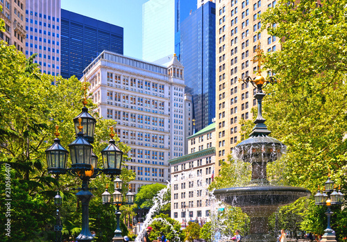 new york spring with green leaves and classic and modern architecture in lower manhattan financial district with water fountain.