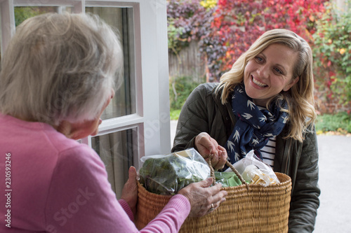 Female Neighbor Helping Senior Woman With Shopping photo