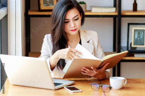 young Asian business woman working at workplace. beautiful Asian woman in casual suit working with reading book, prepare for meeting or interview in modern office. freelance, start up business in Asia