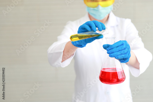 scientist woman with equipment and laboratory glassware holding chemical liquid and checking result using as science research background