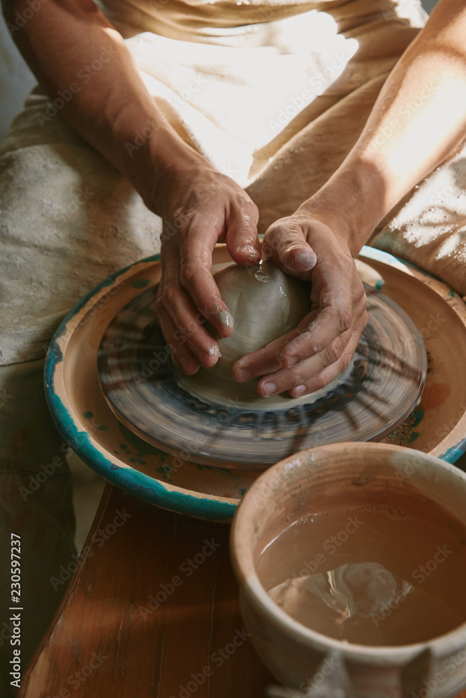 partial view of professional potter working with clay at workshop