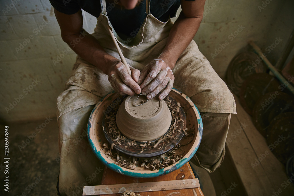 cropped image of professional potter decorating clay pot at workshop