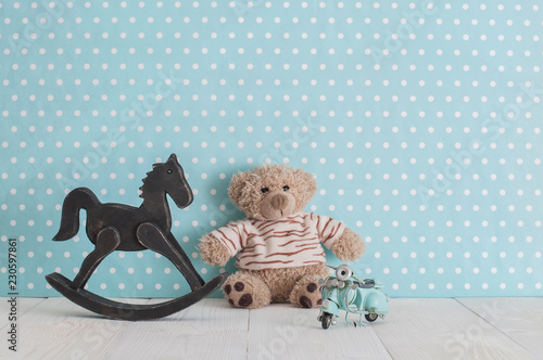 Old wooden toy horse rocking chair, teddy bear and blue vintage motorcycle in baby's room
