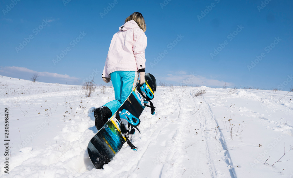 Girl snowboarder with a snowboard on a white snow.