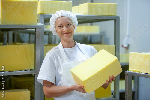 Female worker on yellow cheese production line in an industrial factory