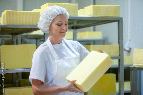 Foto Female worker on yellow cheese production line in an industrial factory
