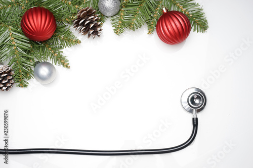 Celebrating Christmas in the healthcare industry. Top view of flat lay. Stethoscope with ornaments on a white background.