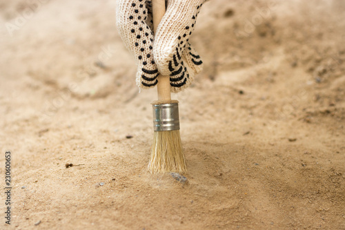 archeology female hand holds brush a tassel excavation of rare materials treasure hunt and archeology find rare resources in sand