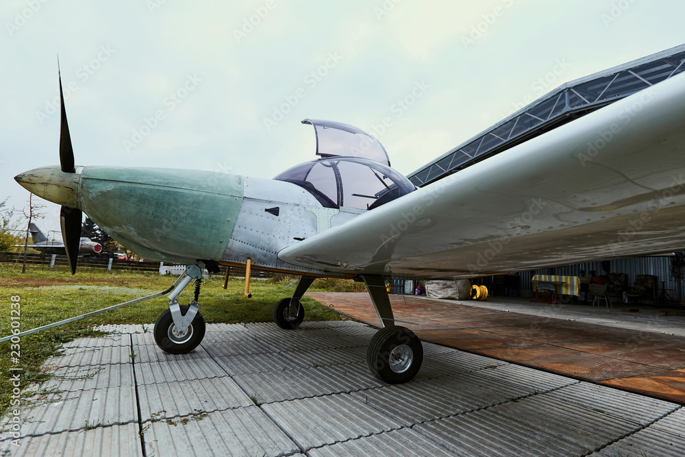Light single-engine aircraft in the summer before the storage hangar. Light single-engine aircraft in the summer before the storage hangar.