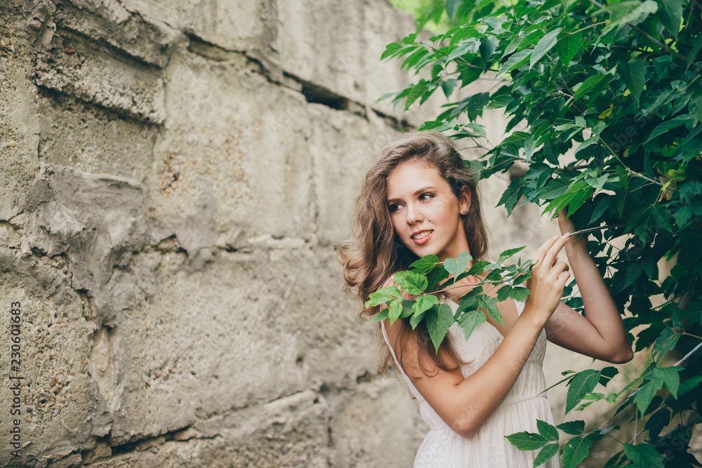 Beautiful happy girl with curly natural hair in white dress near green tree leaves. Summer beauty portrait. Dreamer lady enjoy nature. Inspired woman with dreamy sight in long tunnel in forest. Beautiful happy girl with curly natural hair in white dress near green tree leaves. Summer beauty portrait. Dreamer lady enjoy nature. Inspired woman with dreamy sight in long tunnel in forest.