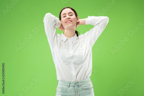 Happy business woman standing and smiling isolated on green studio background. Beautiful female half-length portrait. Young emotional woman. The human emotions, facial expression concept