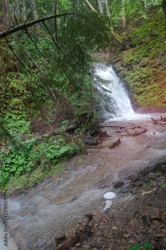 Beautiful forest waterfall in Europe. Small fast rivulet in the mountains with a beautiful view. Stock photo for design