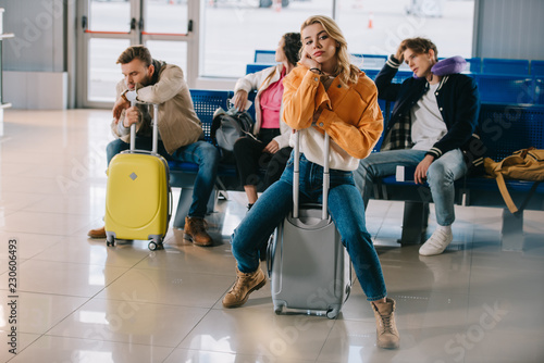 bored young people with luggage waiting for flight in airport terminal