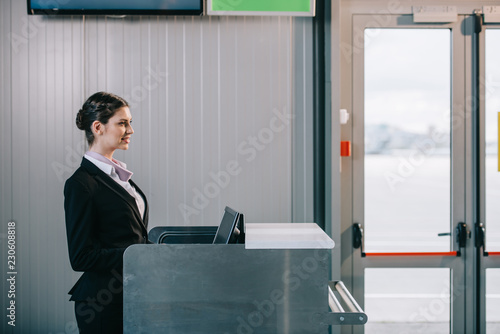 Wallpaper Mural side view of beautiful young female worker at check-in desk in airport Torontodigital.ca
