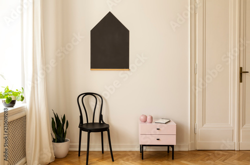 Real photo of a living room interior with a chair, cabinet and house shaped blackboard on the wall © Photographee.eu