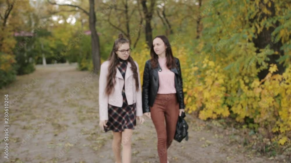 Mother and daughter a teenager walking in the autumn alleys together. Mother and daughter a teenager walking in the autumn alleys together.