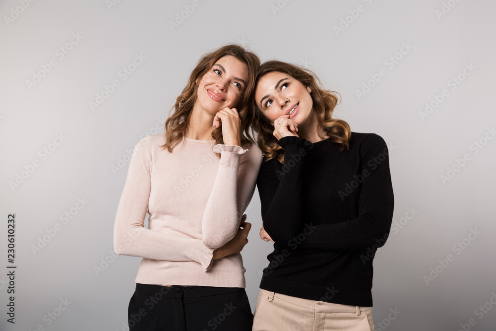 Image of two teenage girls smiling and posing together, isolated over gray background Image of two teenage girls smiling and posing together, isolated over gray background