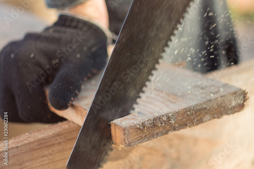 saw boards with a hand saw on a tree, a saw of a tree with a hacksaw