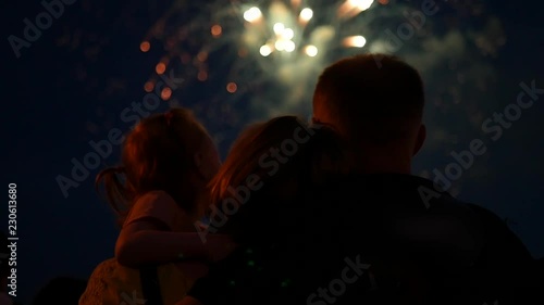 A young family with a daughter in their hands are standing watching the salute in the night sky. slow motion, 1920x1080, full hd