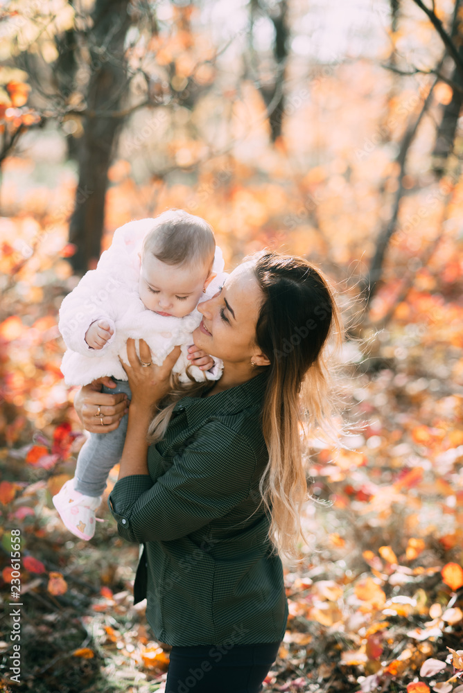 Young mother with little girl in autumn forest with a beautiful colored background Young mother with little girl in autumn forest with a beautiful colored background