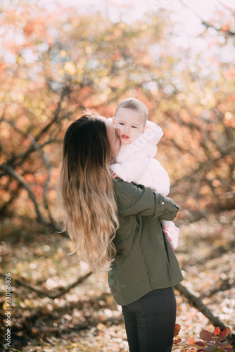 Young mother with little girl in autumn forest with a beautiful colored background