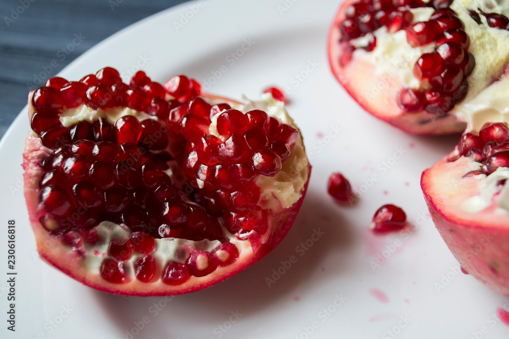 Pomegranate on a white plate. Close up. Pomegranate on a white plate. Close up.
