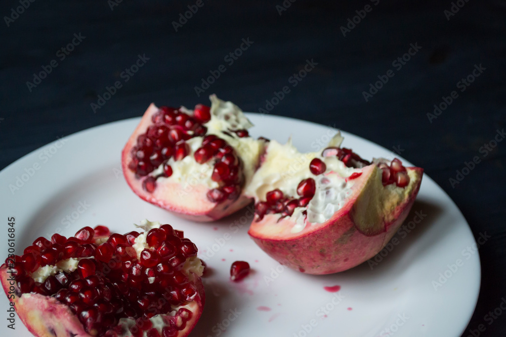 Pomegranate on a white plate. Close up. Pomegranate on a white plate. Close up.