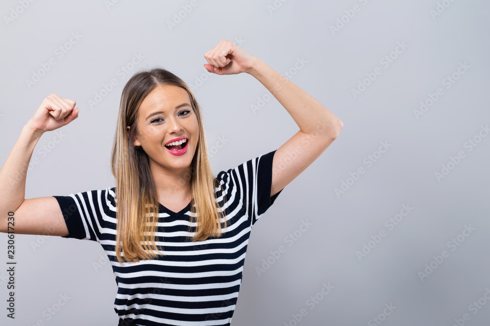 Powerful young woman in a success pose on a gray background Powerful young woman in a success pose on a gray background