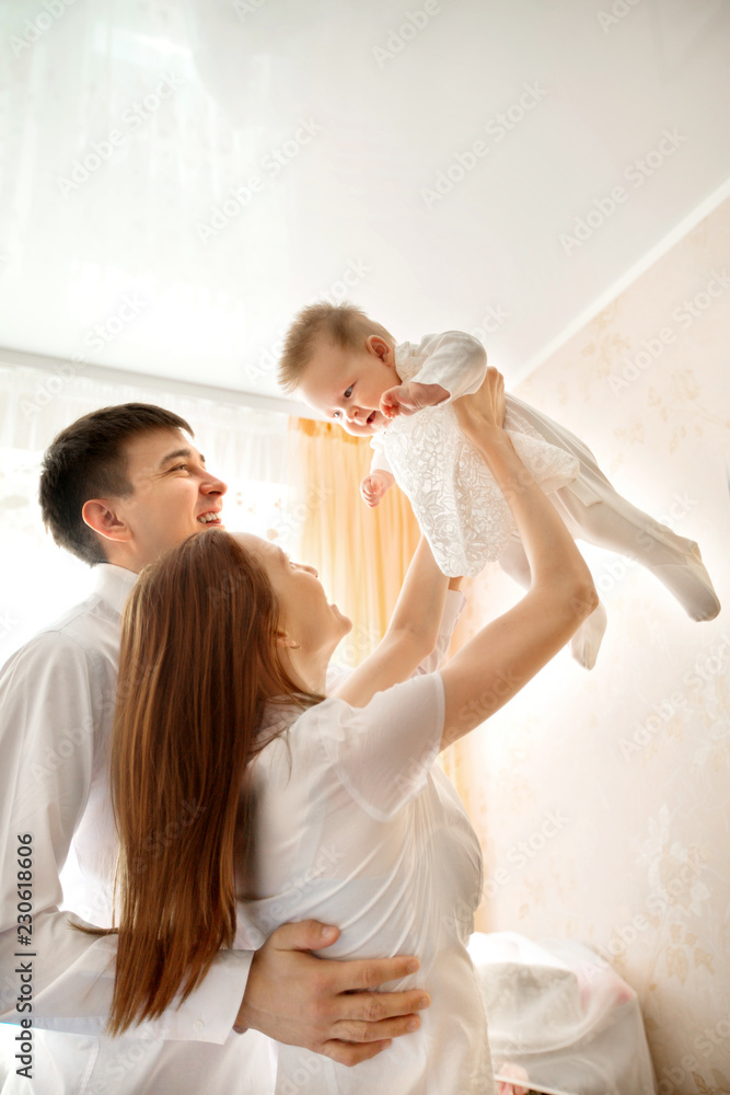 Fototapeta premium beautiful young parents mom and dad are holding their little baby in their arms