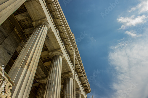 ancient Roman palace architecture facade with marble columns foreshortening from below on blue sky background, copy space 