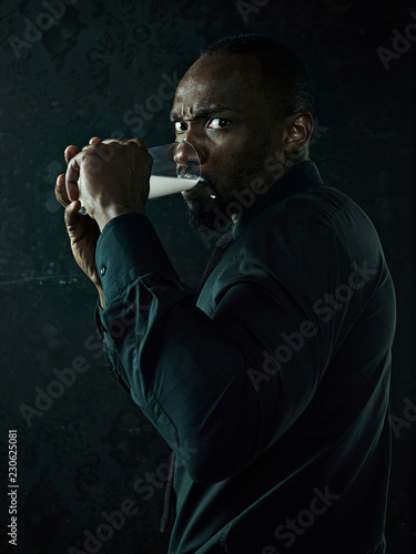 Healthy young african man holging cup of milk on a bllack studio background.