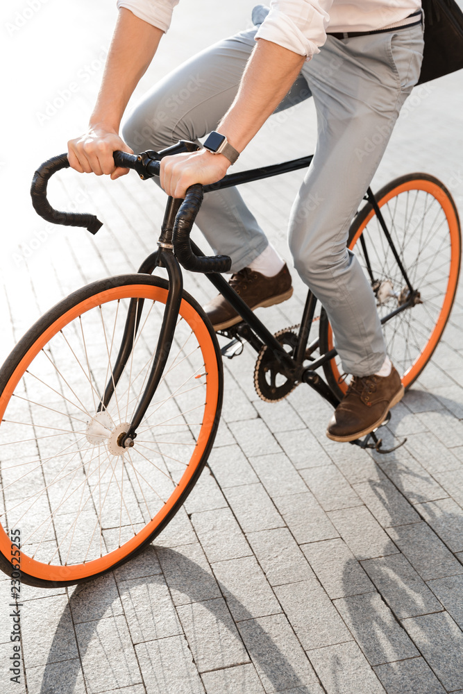 Photo of european man 30s wearing formal clothing, riding on bicycle on city street Photo of european man 30s wearing formal clothing, riding on bicycle on city street