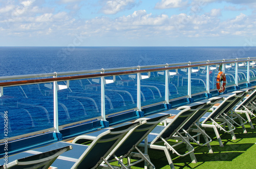 View from the deck of a cruise ship in the ocean. Seating area for passengers  chairs and sun loungers. Sunbathe.