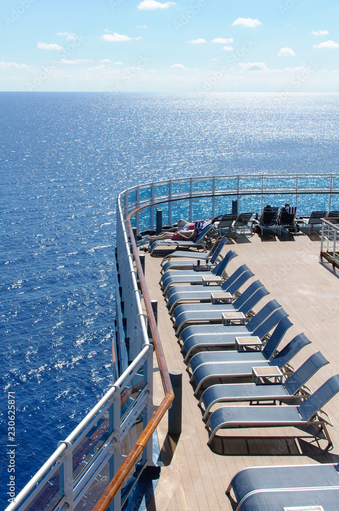 Obraz premium View from the deck of a cruise ship in the ocean. Seating area for passengers, chairs and sun loungers. Sunbathe.