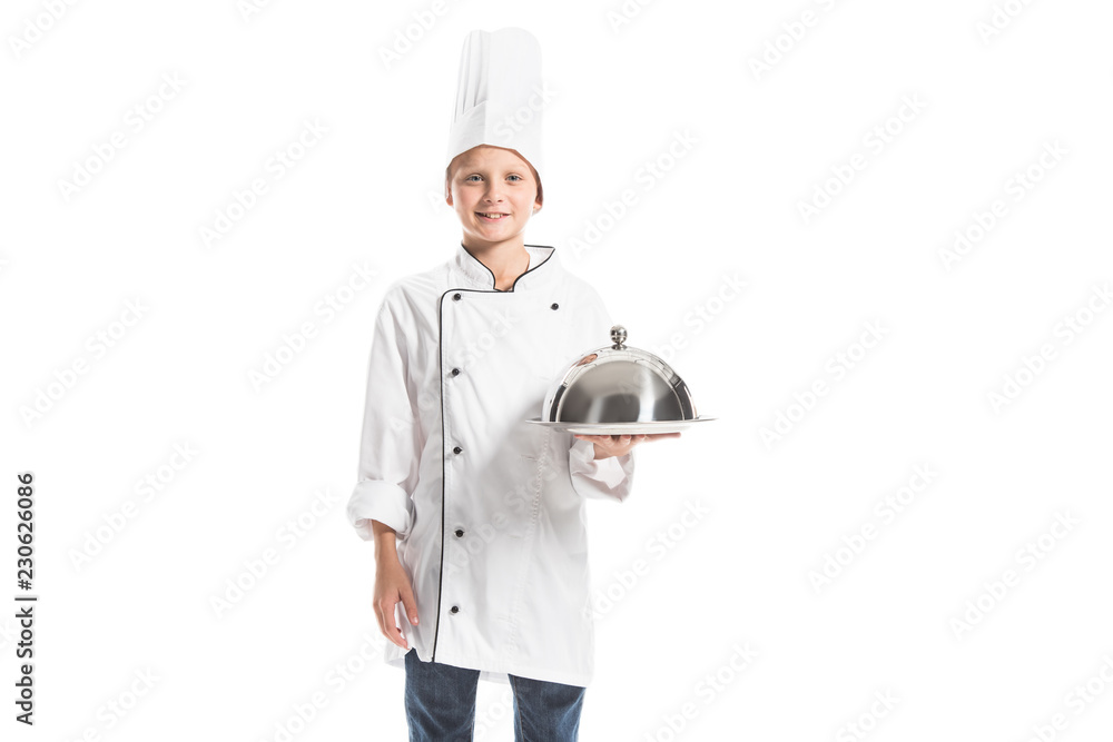 smiling boy in chef uniform and hat holding metal serving tray isolated on white smiling boy in chef uniform and hat holding metal serving tray isolated on white
