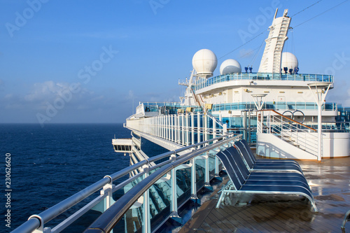 View from the deck of a cruise ship in the ocean. Seating area for passengers, chairs and sun loungers. Sunbathe.