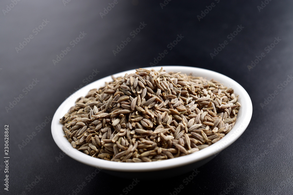 cumin jeera seeds , indian spices, ceramic bowl on black background cumin jeera seeds , indian spices, ceramic bowl on black background